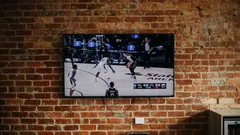 Basketball game on TV mounted on brick wall in living room